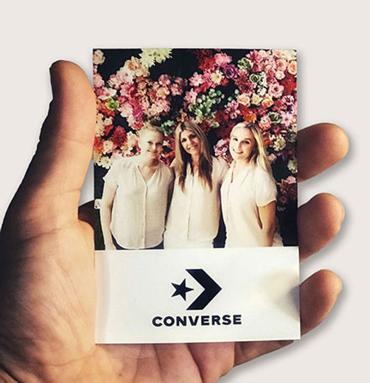 Three people in front of a floral backdrop holding a photo.