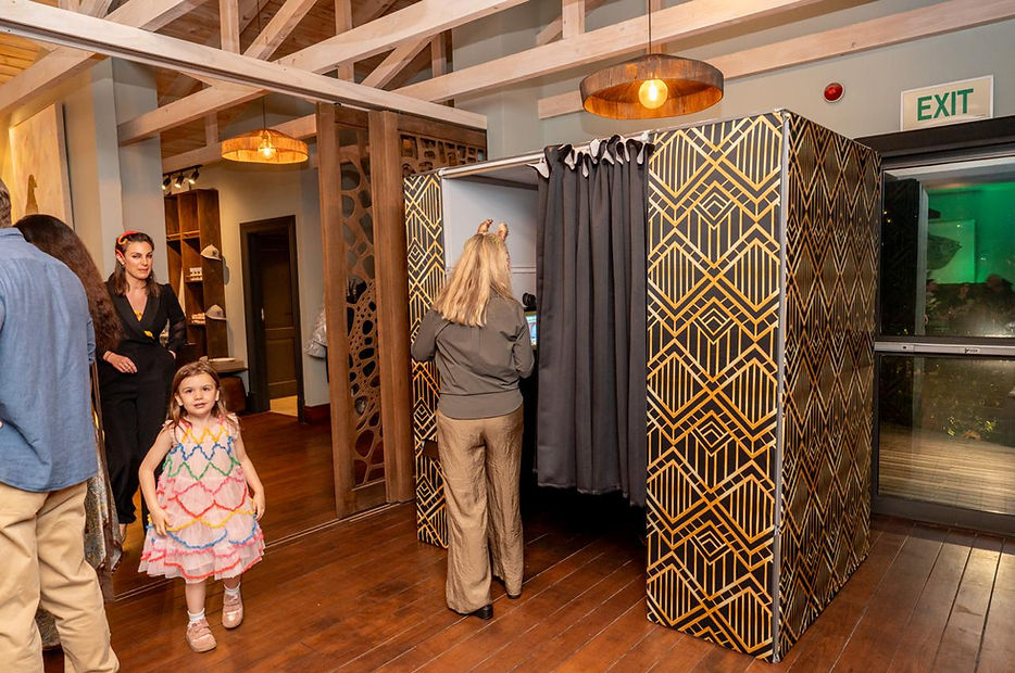 A black and gold photo booth with guests nearby.