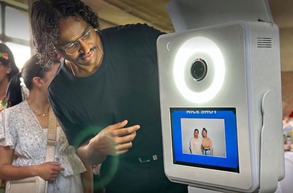A man interacting with a photo booth display showing photos.