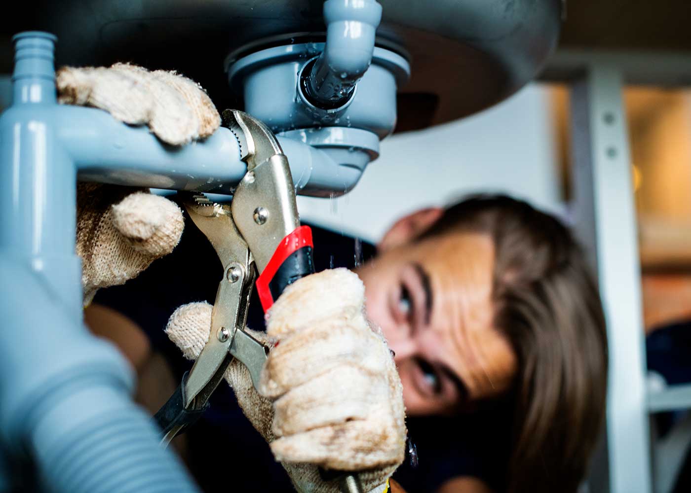 A plumber repairing plumbing under a sink