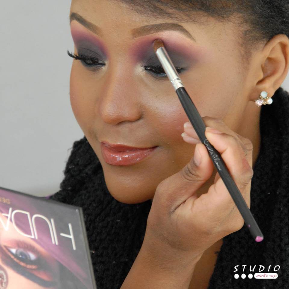 Makeup artist applying purple eyeshadow to a client.