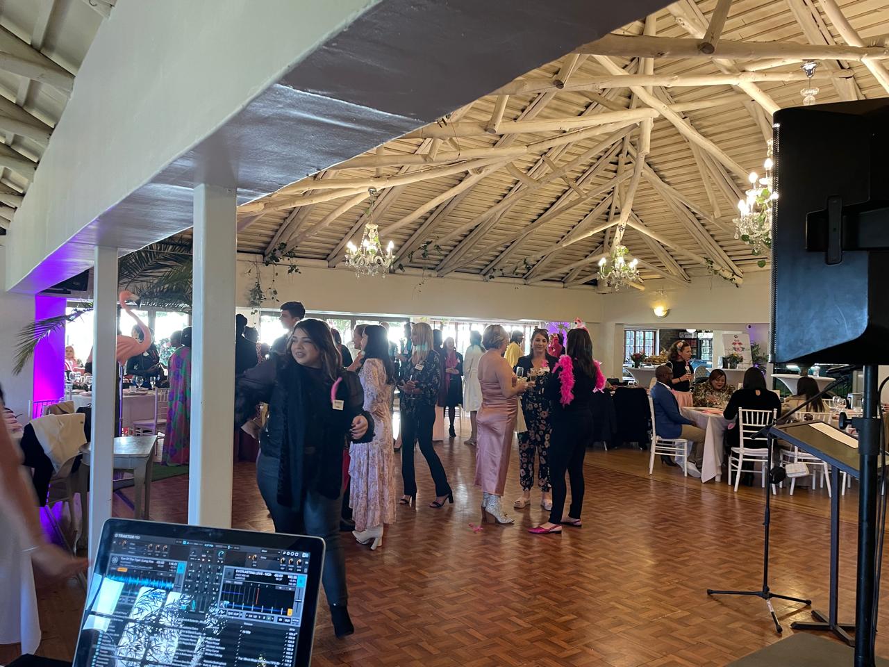 Crowd dancing in a well-lit venue with DJ equipment