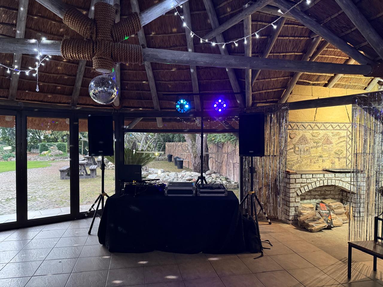 DJ setup with speakers and lighting in a rustic venue