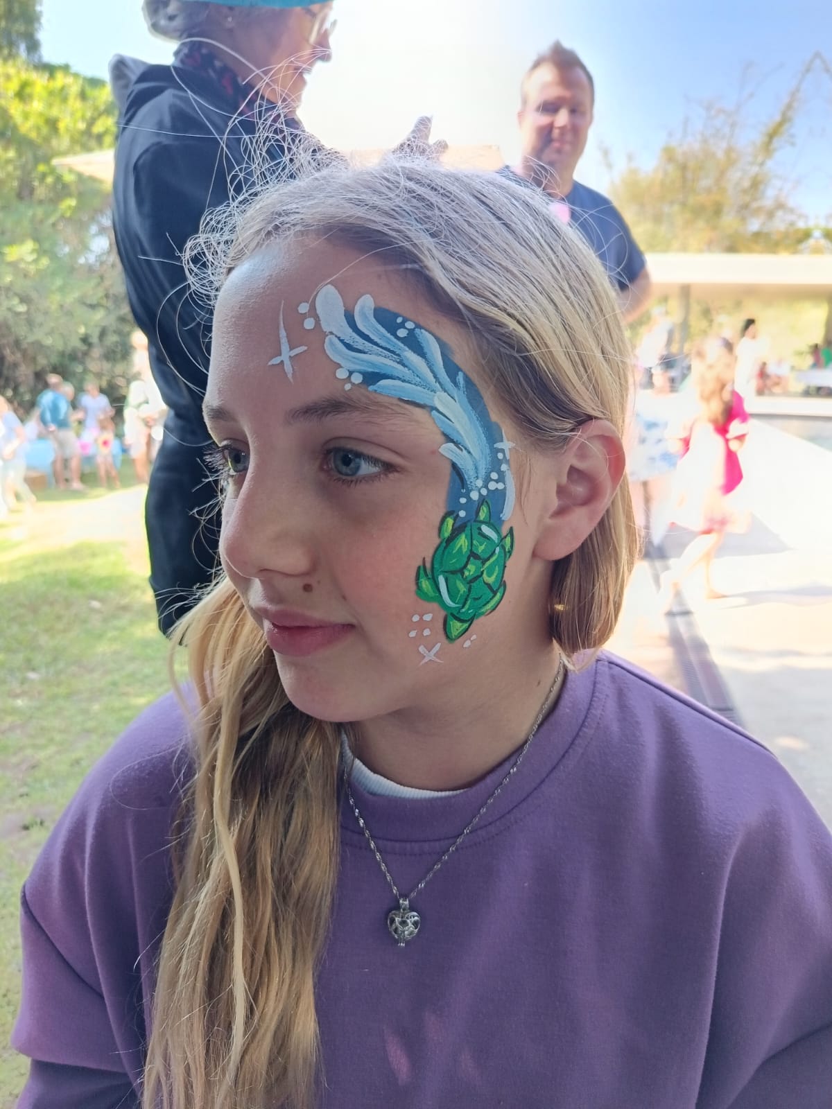 Child with colorful face painting of waves and a sea creature
