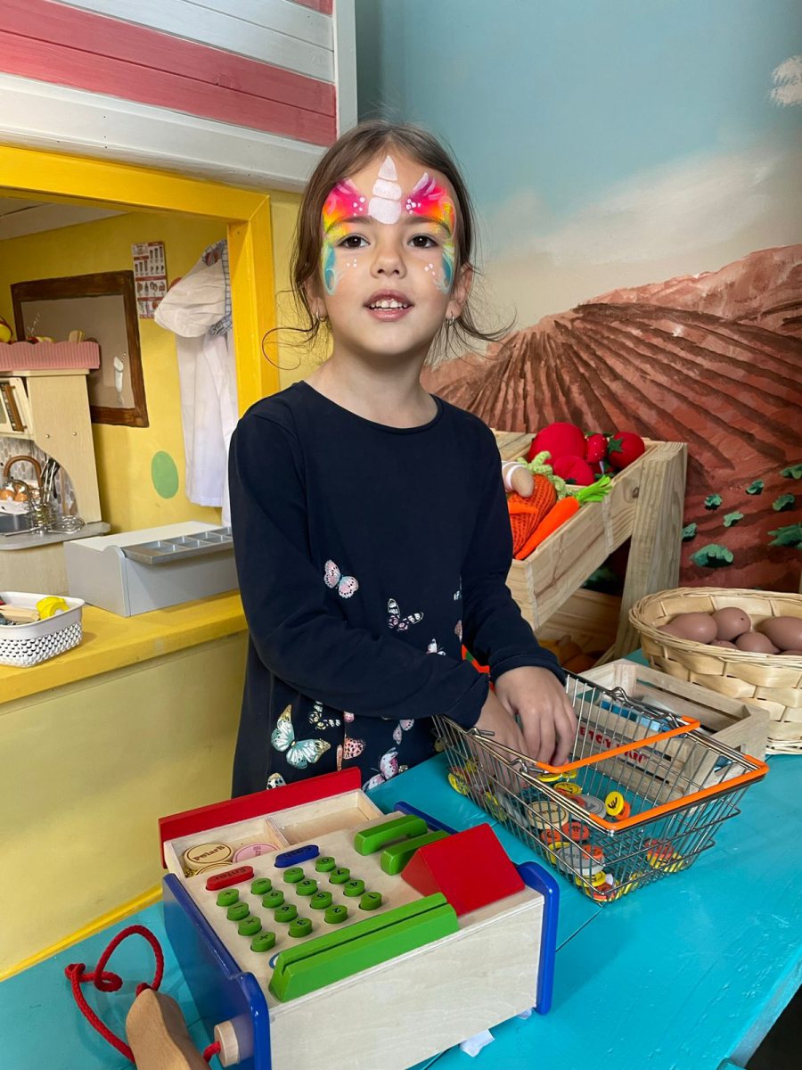 Child with colorful face paint at a play area
