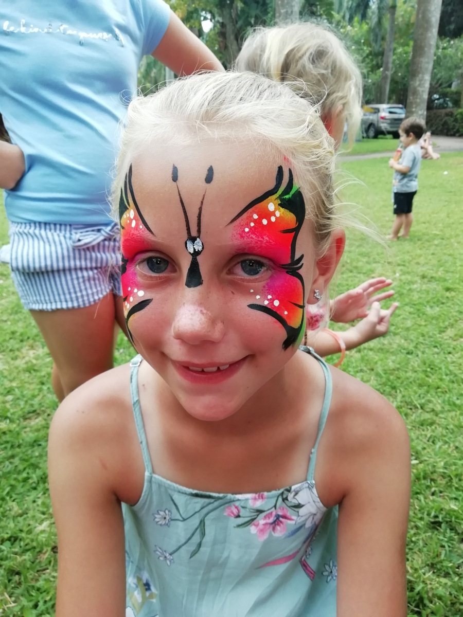 Girl with butterfly face painting in a grassy area