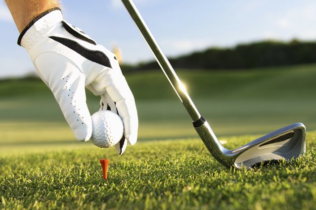A golfer preparing to tee off with a club and golf ball