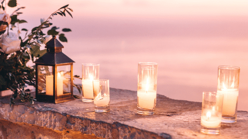 Various candles lit on a stone ledge with a lantern