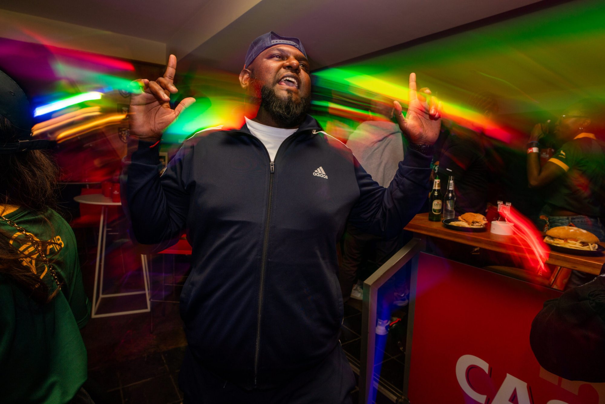 A man celebrating at a lively event with colorful lighting