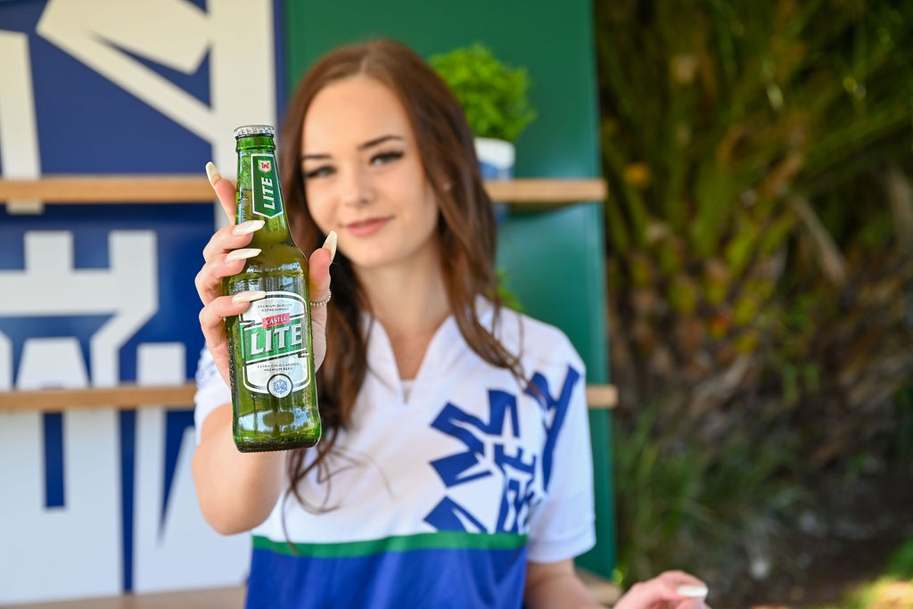 A woman holding a bottle of beer in front of a green background