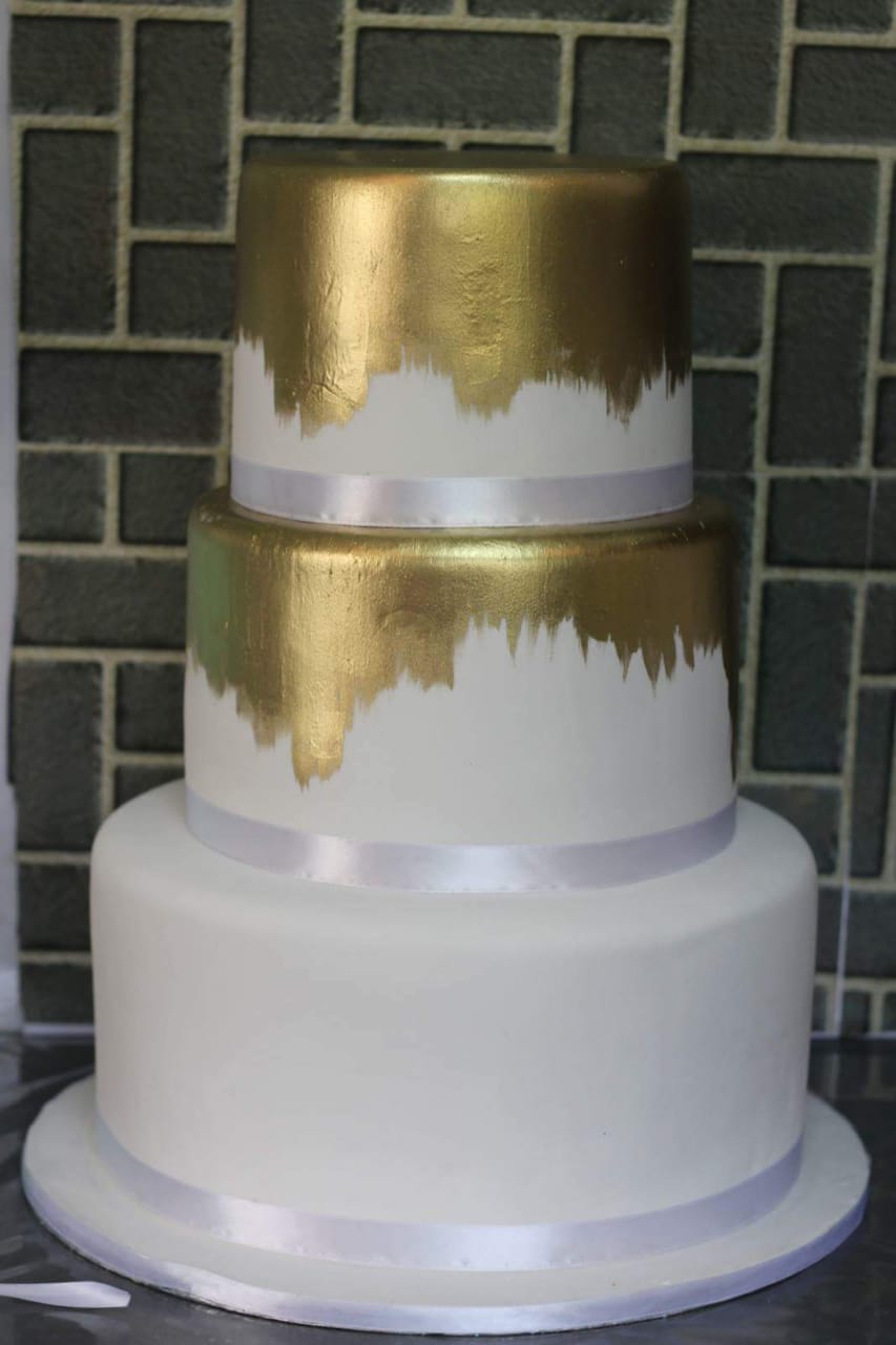 Two-tier wedding cake with gold and white decoration.