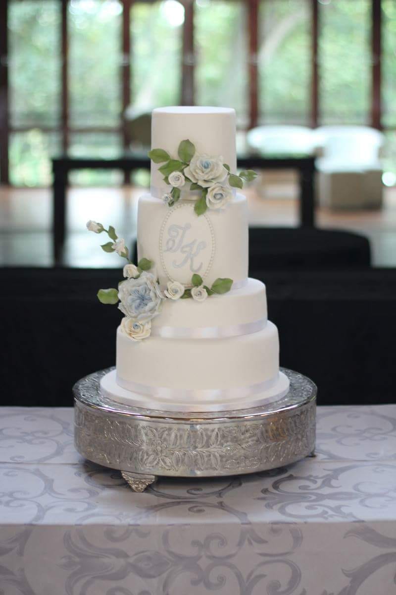 White three-tier wedding cake with blue roses and initials