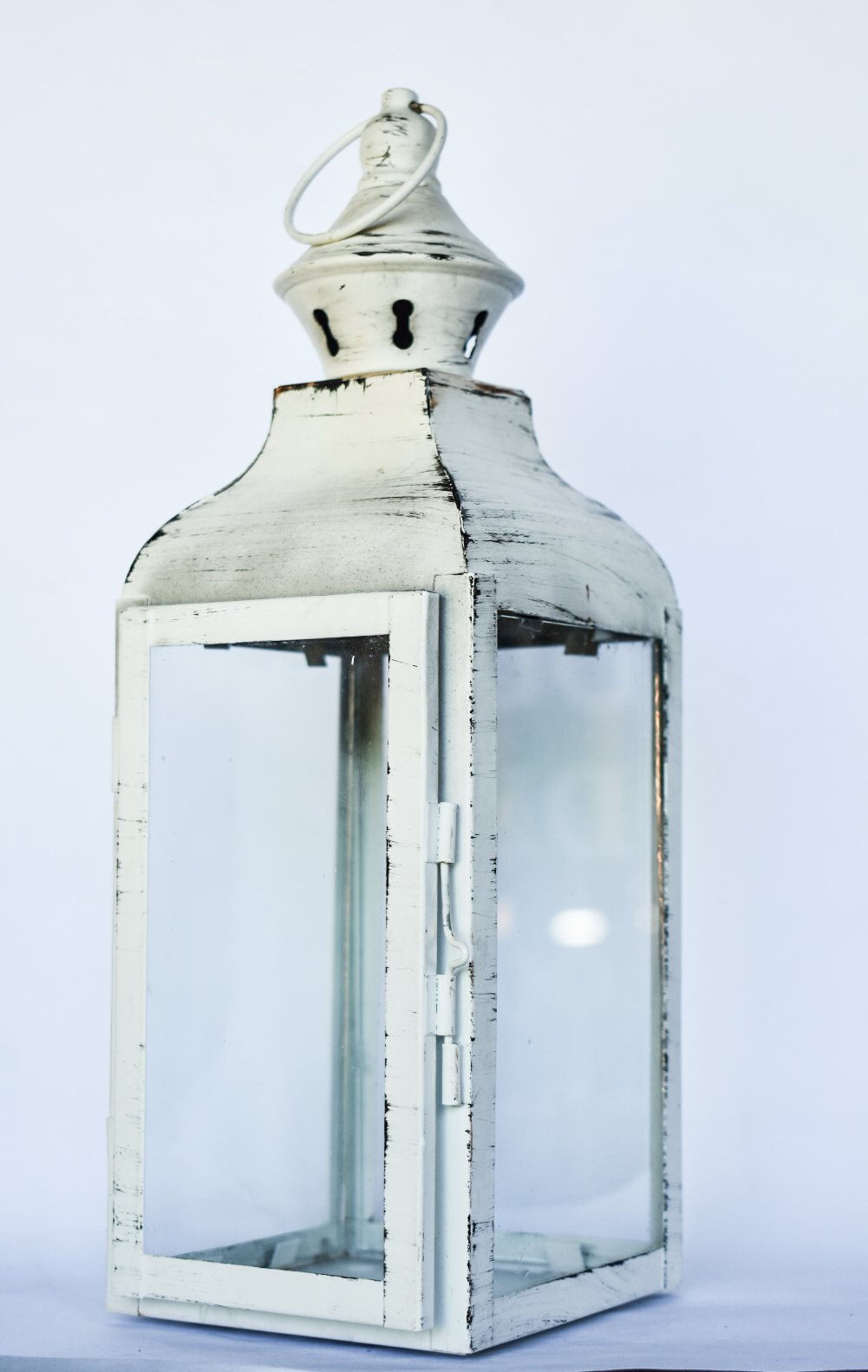 A vintage white lantern with a glass enclosure