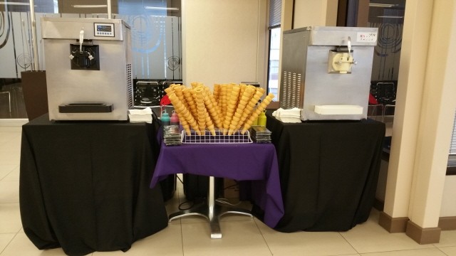 Two soft serve ice cream machines with serving cones and colorful cups