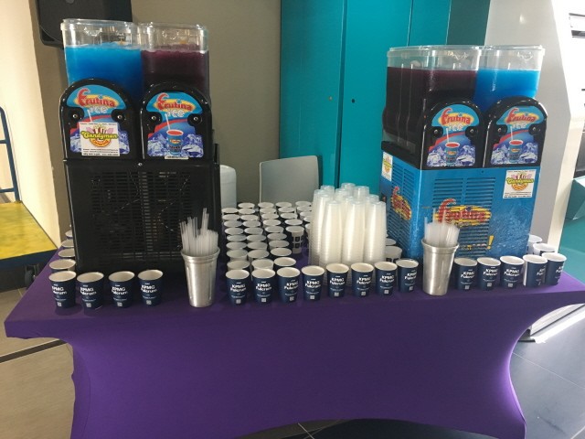 Two slushie machines with cups and straws on a table
