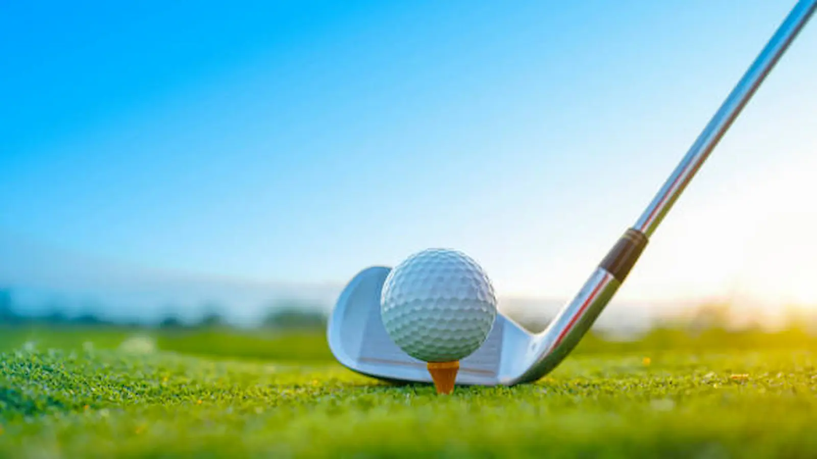 Golf club and ball on a tee under a clear sky