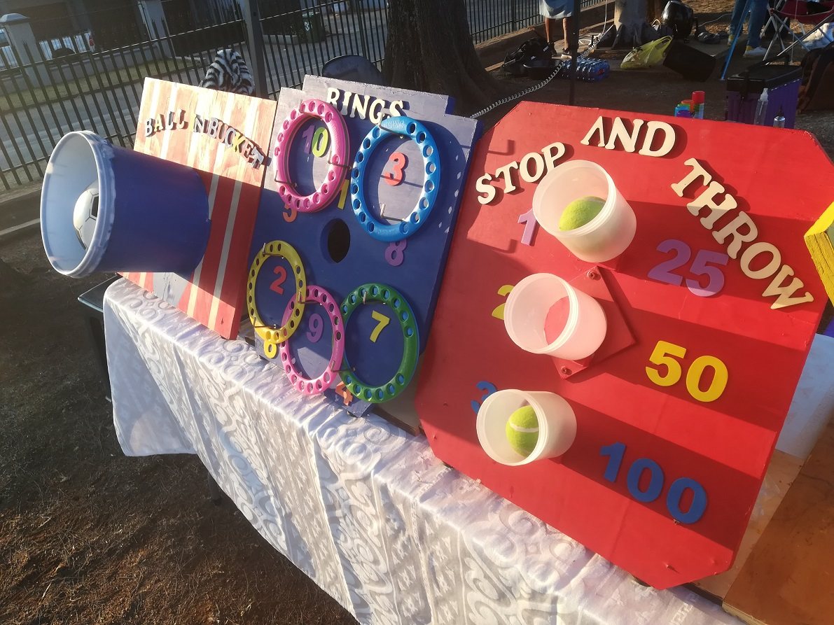 Colourful carnival games including ring toss and ball throwing.