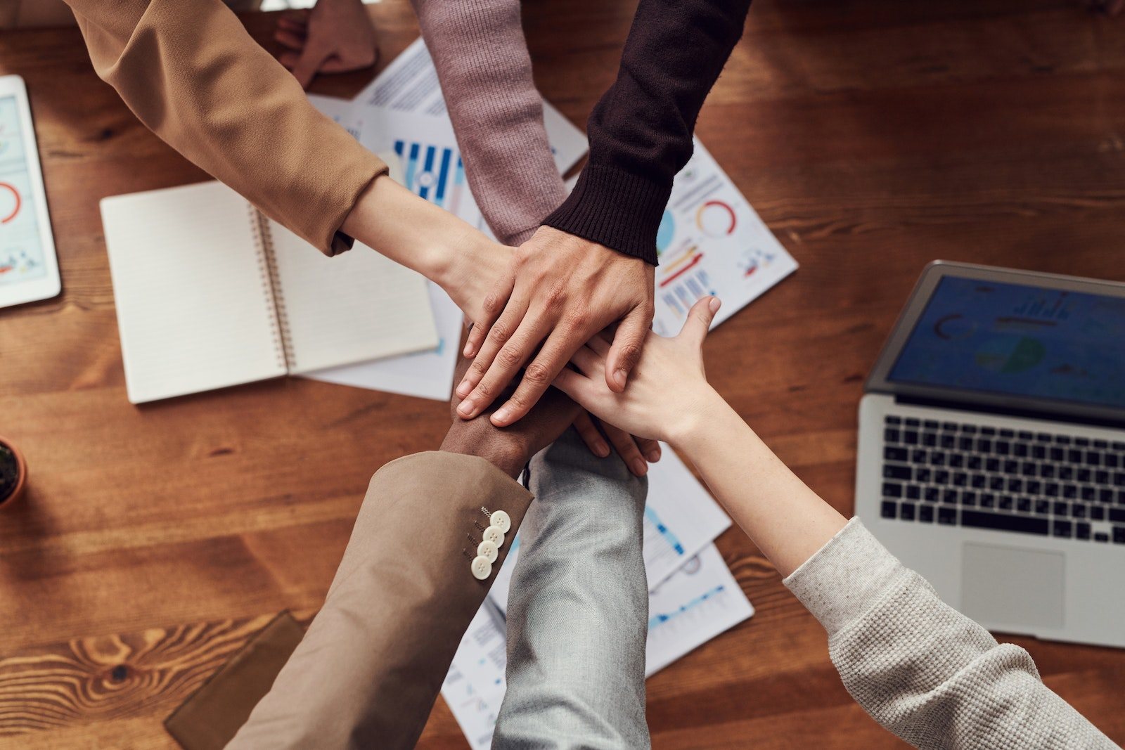 Hands stacked together in a team collaboration setting.