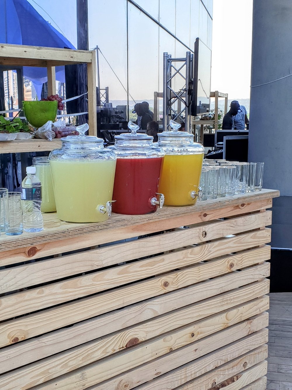 Three drink dispensers with colorful beverages on a wooden bar