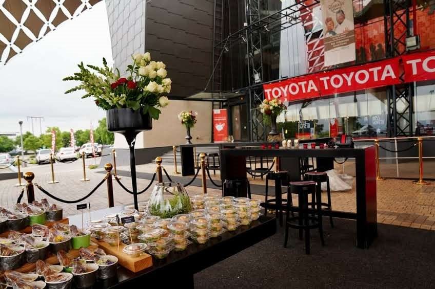 Catering table with assorted dishes and flowers outdoors.