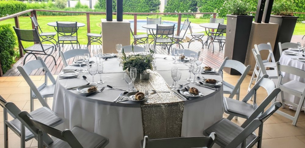 Round table with silver runner and white chairs