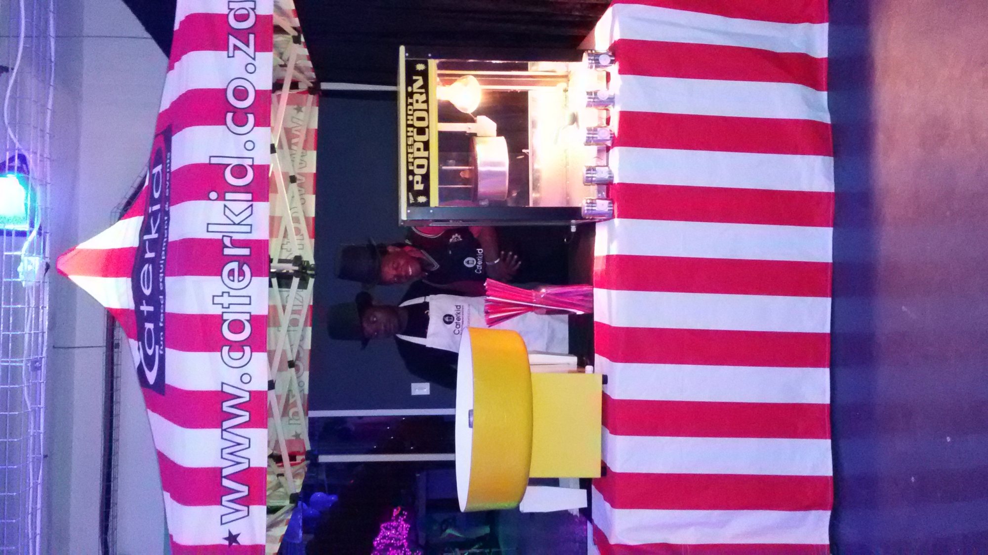 Popcorn station with striped canopy and staff serving popcorn