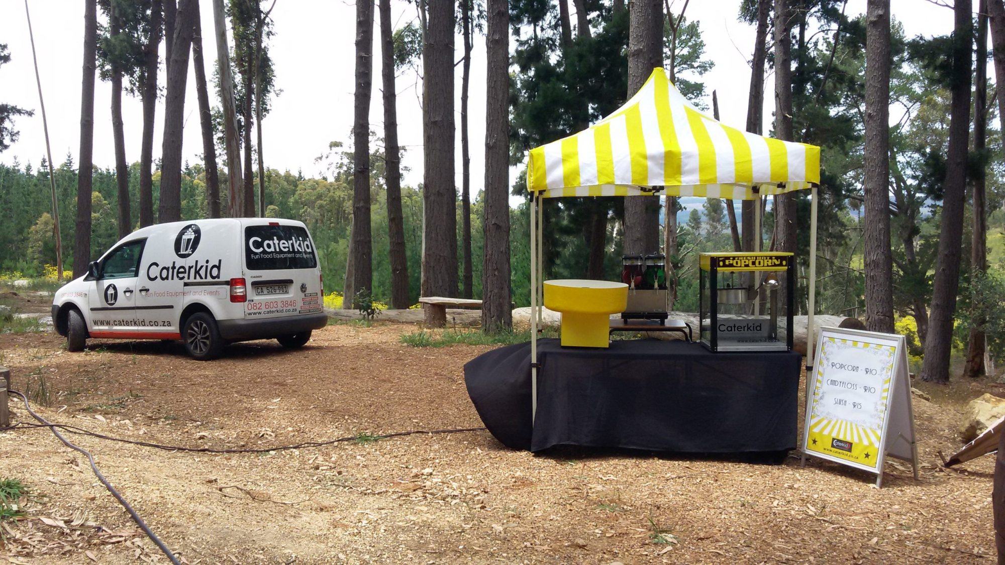 Caterkid event setup with a tent, food station, and van in a forest
