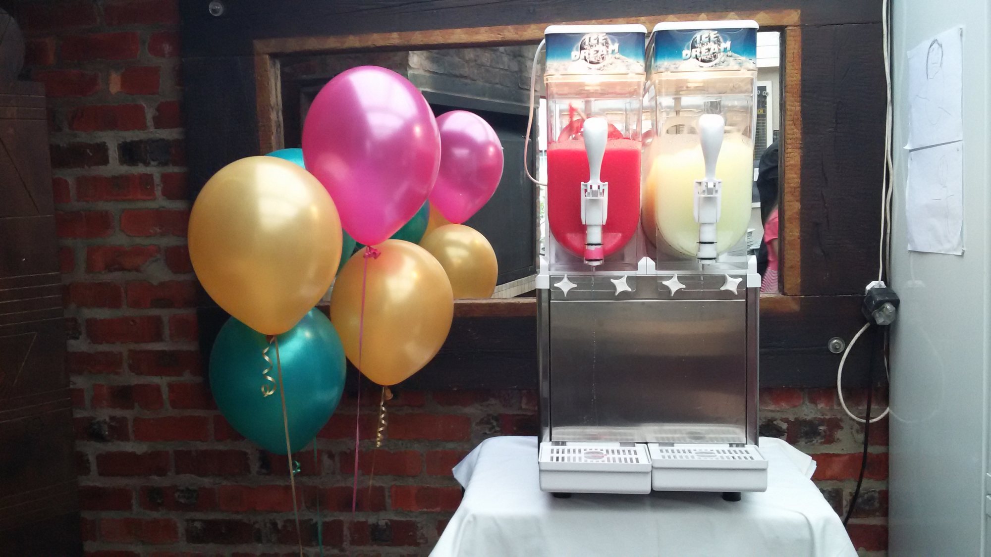Slushie machine with colorful balloons in background