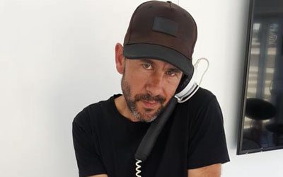 Male DJ holding a telephone receiver to his ear.