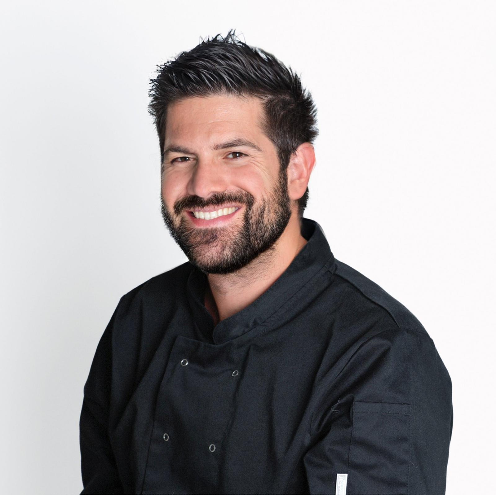 Portrait of a smiling head chef in a black uniform.