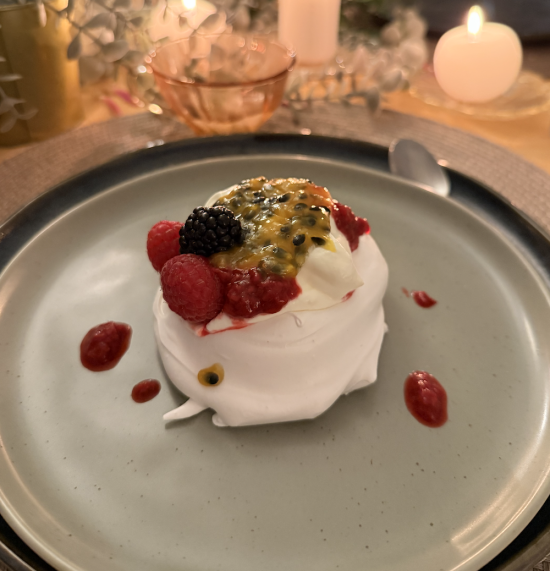 Vegan pavlova topped with berries and passion fruit on a plate
