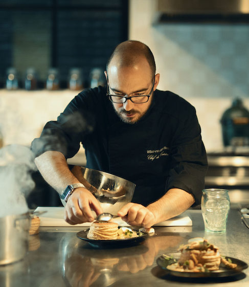 Chef carefully plating a dish in a kitchen setting