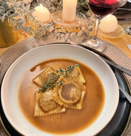 Bowl of ravioli in broth with thyme garnish