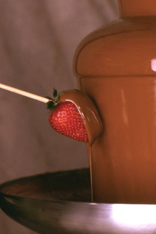 Close-up of a chocolate fountain with a strawberry being dipped