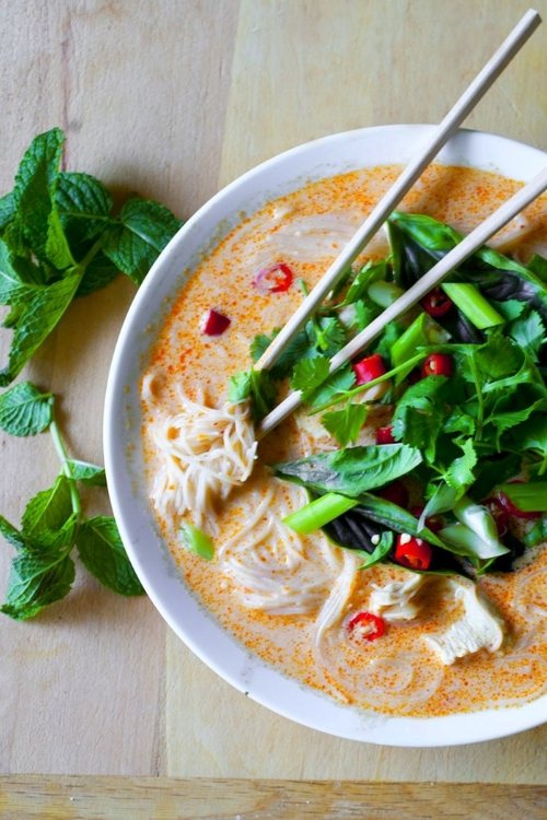 A bowl of gourmet noodles with fresh herbs and toppings