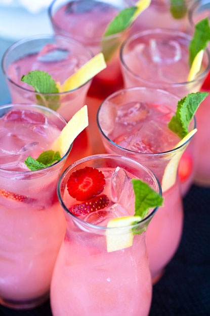 Tall glasses of pink drinks with strawberries and mint leaves