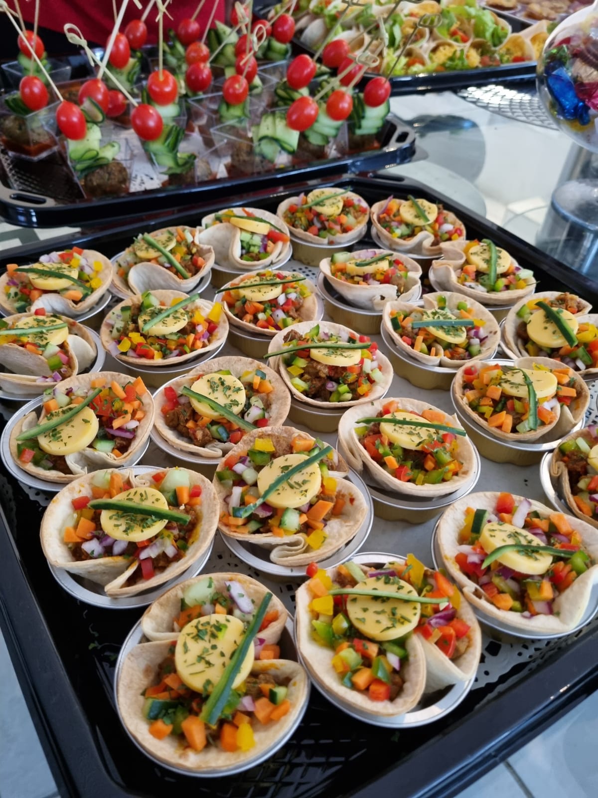 A platter of savory mini tarts with vegetables and toppings.