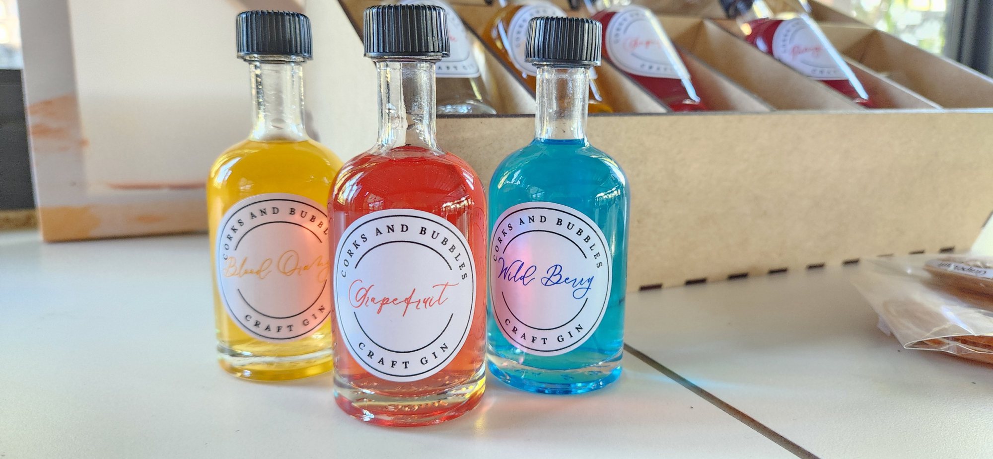 Three mini craft gin bottles in yellow, red, and blue