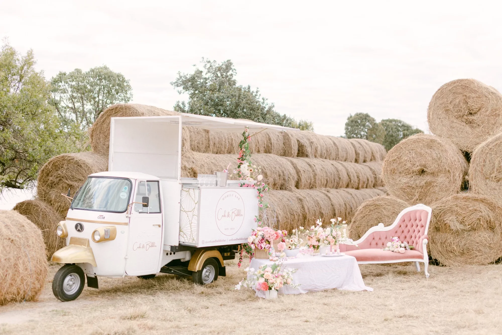 Mobile champagne bar with floral decor near hay bales