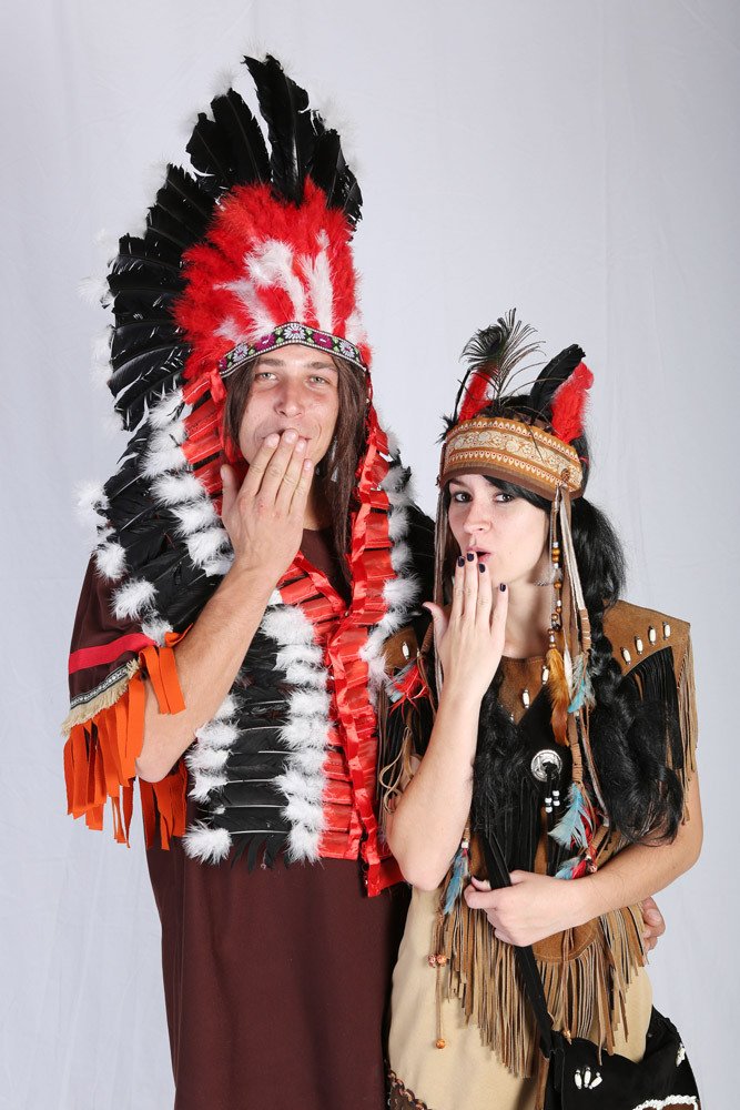 Couple in Native American themed costumes with feathered headdress.