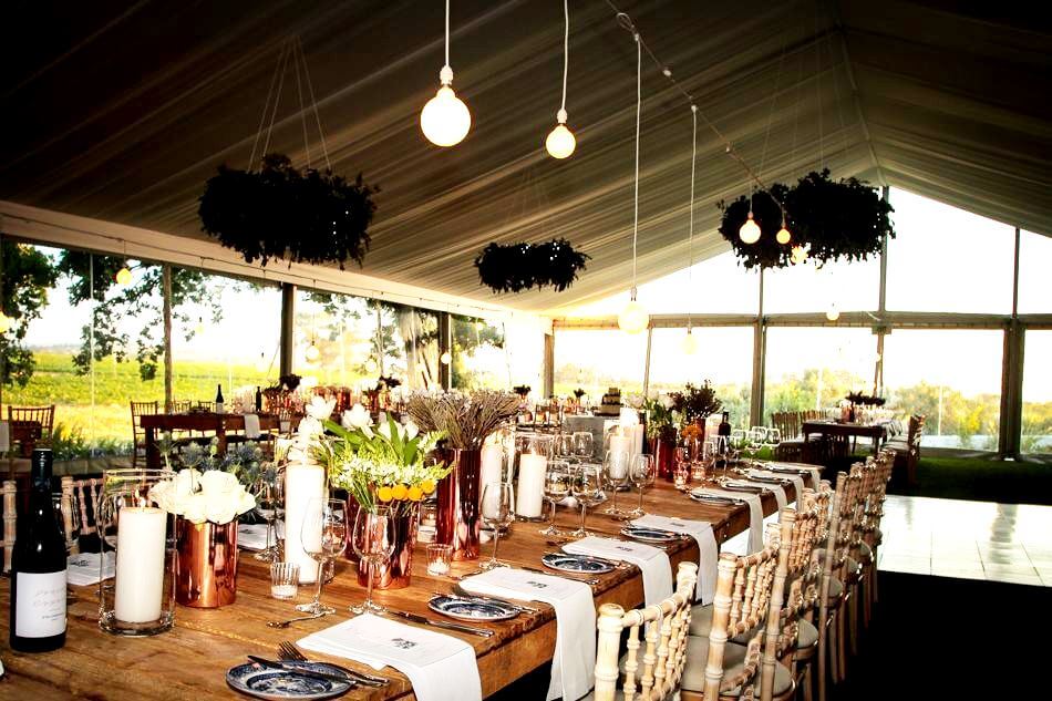Long wooden dining table with floral decorations and pendant lights