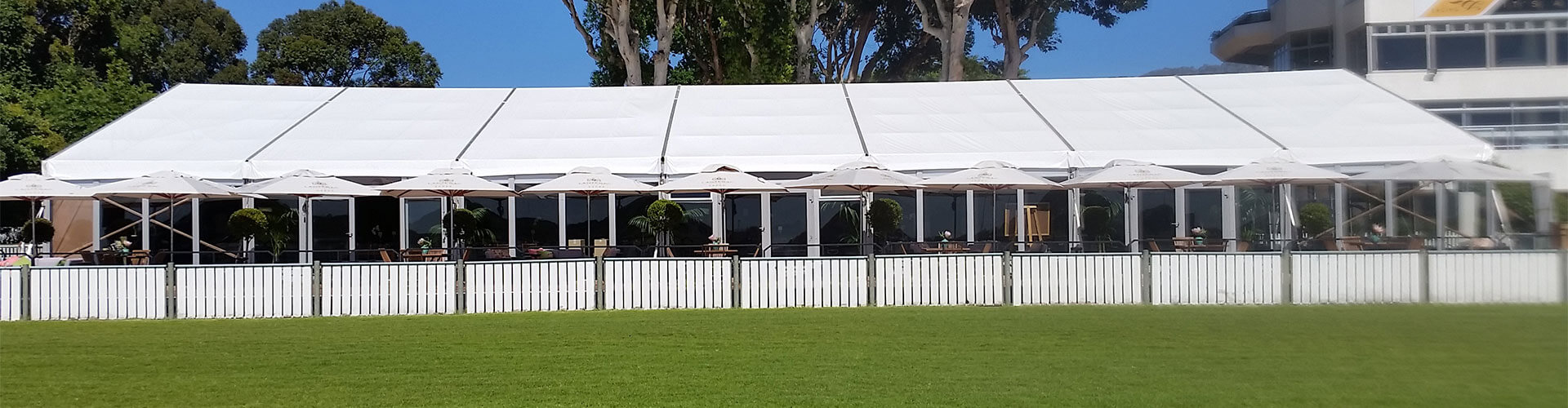 Large white marquee tent with parasols and outdoor seating