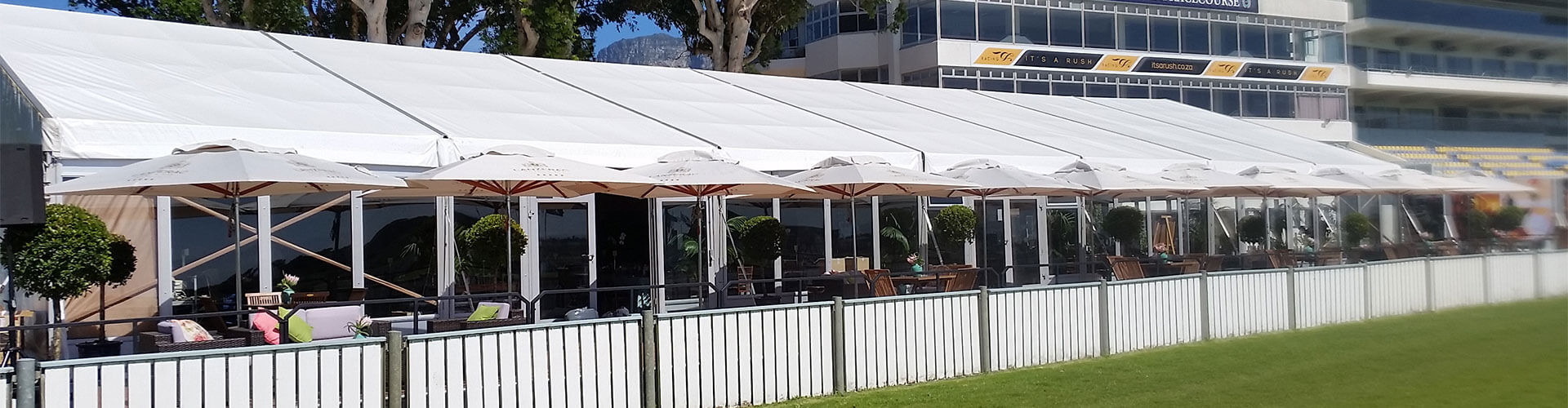Large white marquee with outdoor seating and umbrellas