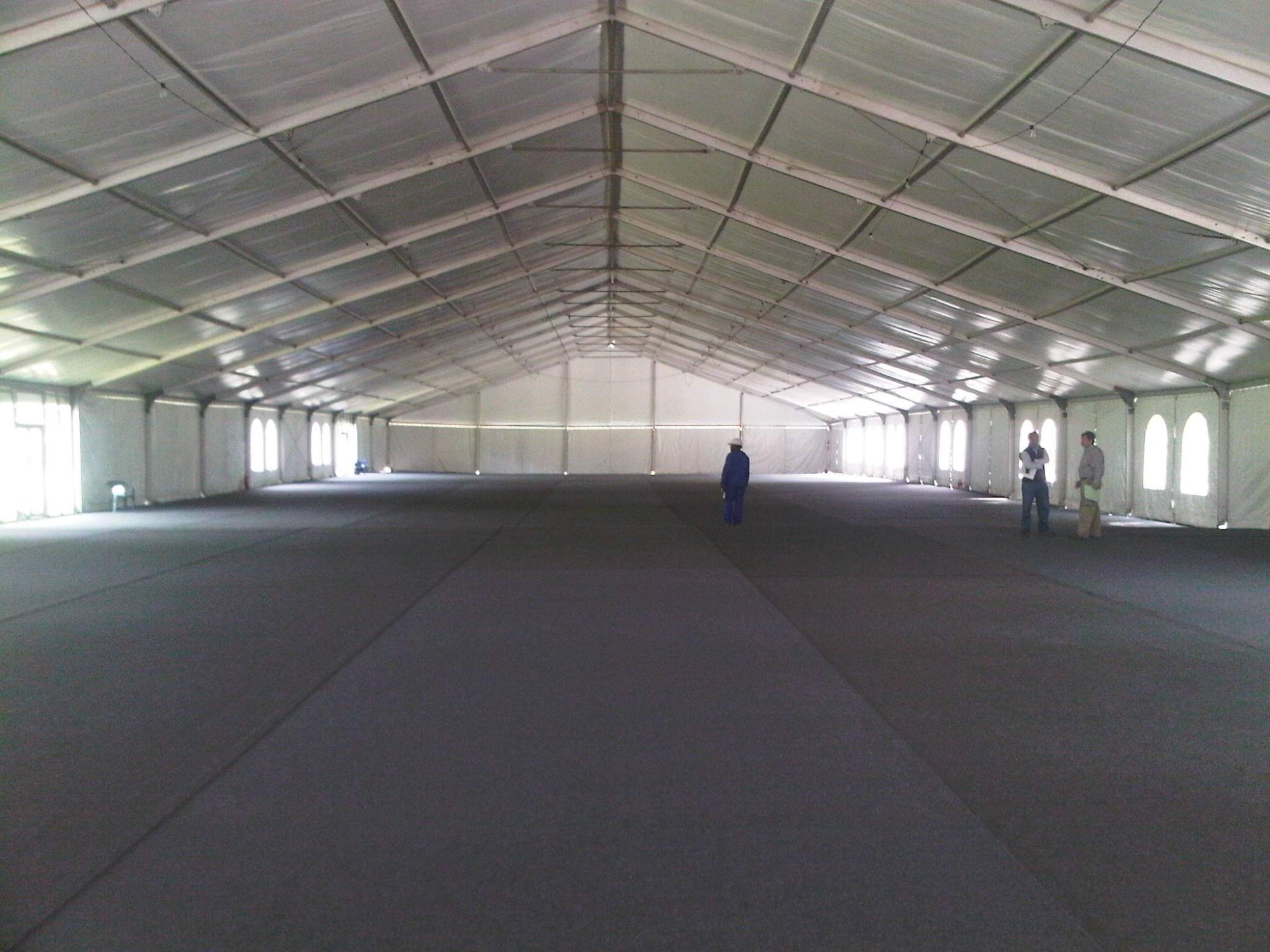 Interior view of a large, empty event tent with grey carpet.