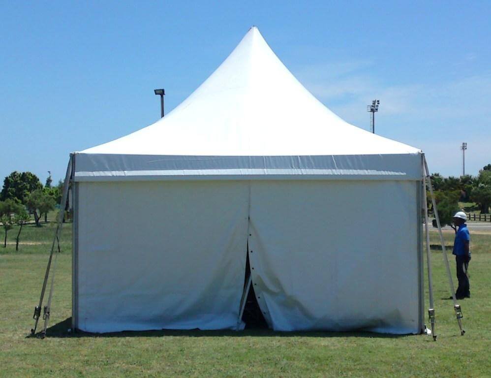 Large white Bedouin tent on grass with a peak roof.