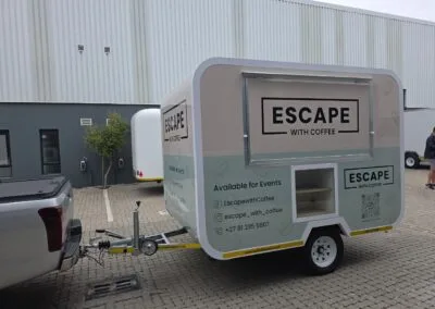 Coffee trailer labeled 'Escape with Coffee' parked on pavement.