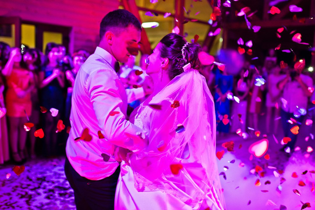Newlyweds dancing surrounded by guests and confetti.