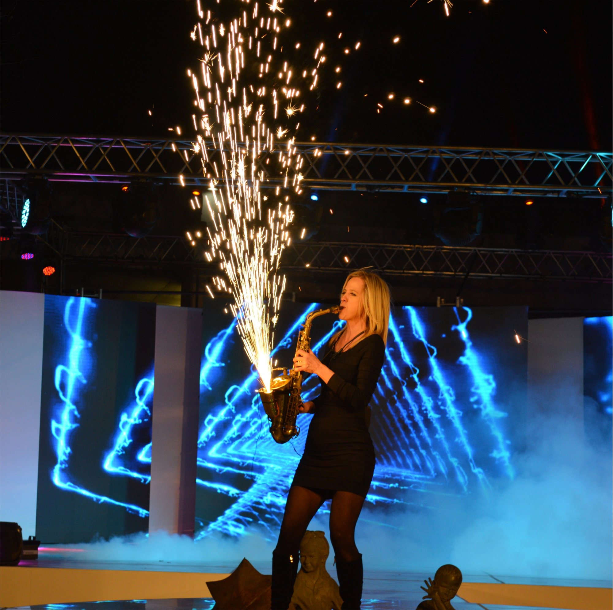 Female saxophonist performing with sparks and lights