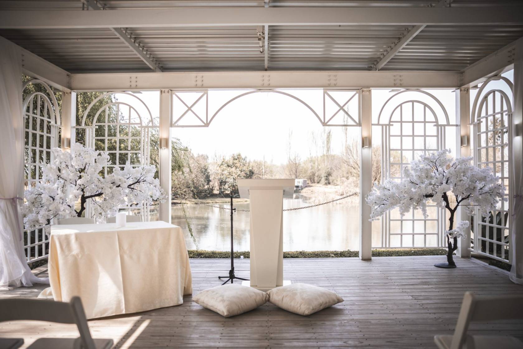 Outdoor wedding ceremony setup with white podium and decorated trees.