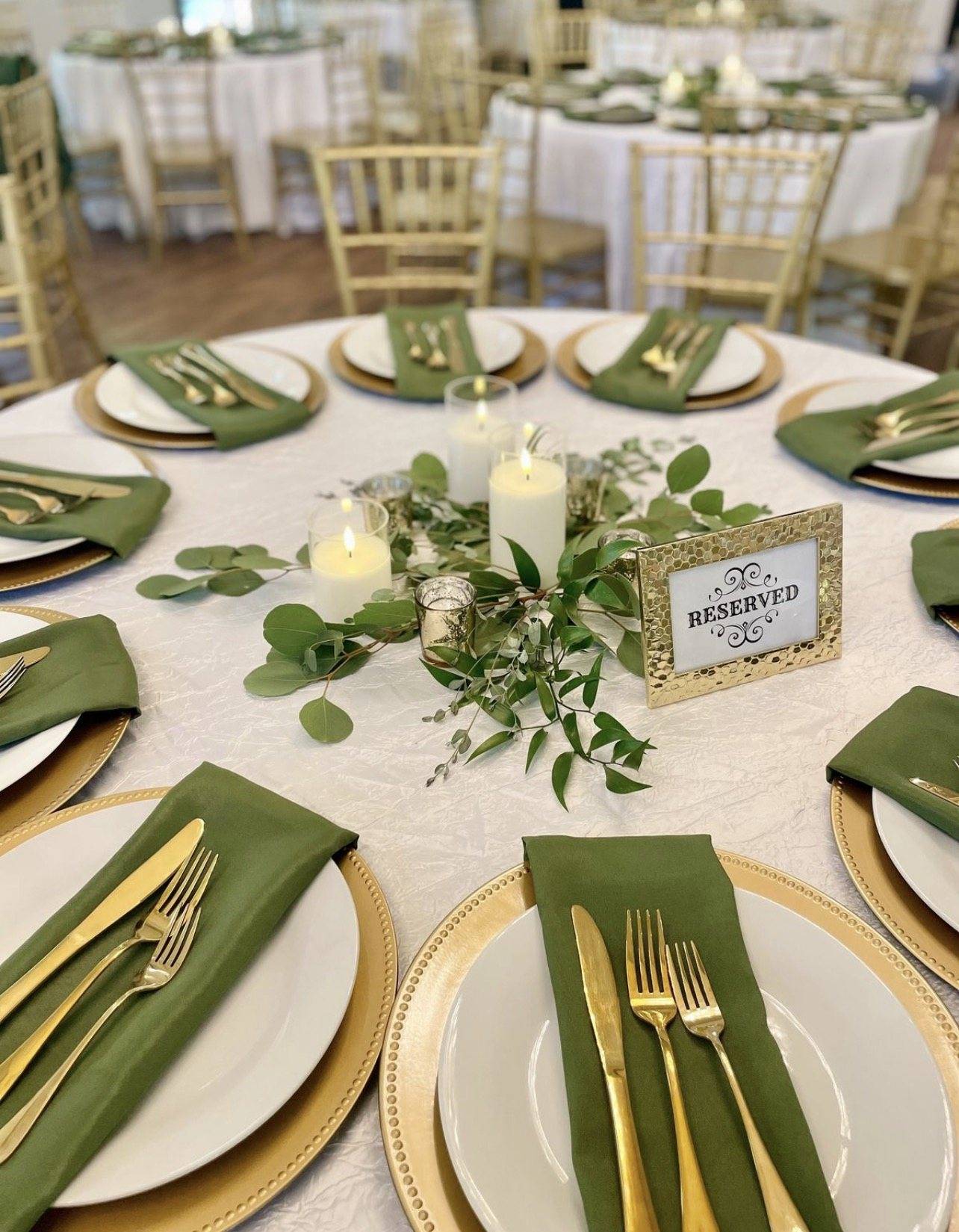 Table set with green napkins, gold cutlery, and reserved sign